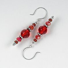 red glass beaded earrings with silver earwires on white background, closeup