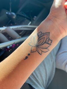 a woman's arm with a lotus tattoo on the left side of her wrist