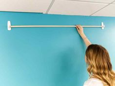 a woman is painting the wall with blue paint and white rollers in an office