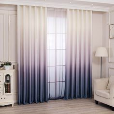 a living room with a white chair and window covered in blue ombreed curtains