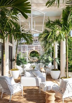 an outdoor living area with white furniture and palm trees