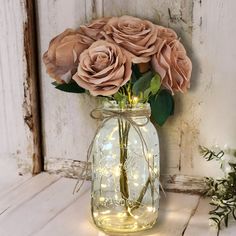 a mason jar filled with pink roses sitting on top of a table