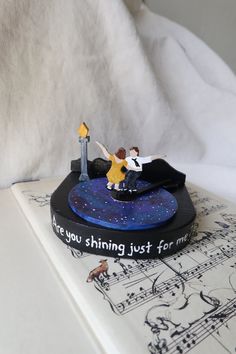 a figurine is sitting on top of a book with music notes around it