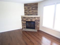 an empty living room with a fireplace and hard wood floors