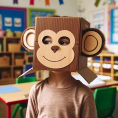 a young boy wearing a cardboard box with a monkey on it's head in a classroom