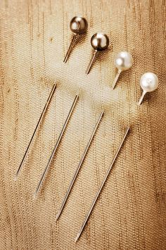 several pins and needles sitting on top of a piece of cloth next to each other