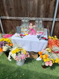 a table topped with lots of flowers next to jars filled with water and cupcakes