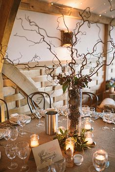 a table set up with candles and flowers in a vase on top of the table