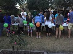 a group of people standing around a table with balloons