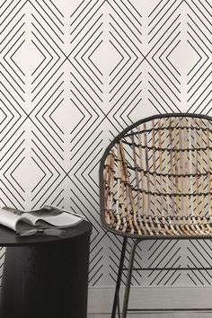 a wicker chair next to a black and white wall with geometric designs on it