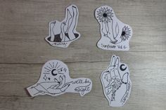 four stickers with different designs on them sitting on top of a wooden table next to each other