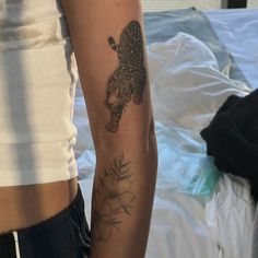 a person with a tattoo on their arm next to another person's hand and bed in the background