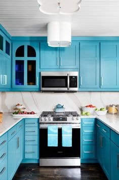 a kitchen with blue cabinets and stainless steel appliances, including an electric stove top oven