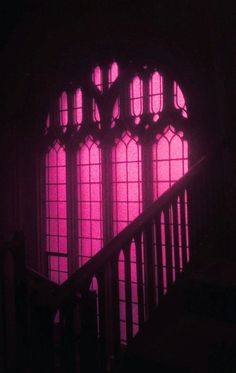 the stairs are lit up with bright purple lights in front of an arched glass window