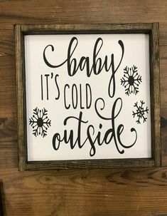 a sign that says baby it's cold outside on the side of a wooden wall