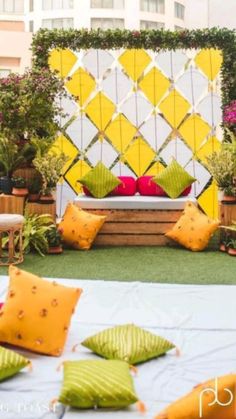 an outdoor seating area is decorated with yellow and green pillows, greenery and potted plants