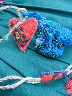 two pieces of fabric with beads and hearts on them sitting on a piece of cloth