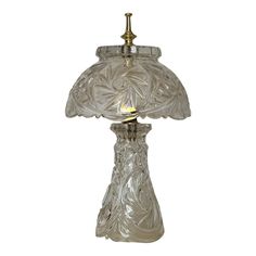 a glass table lamp with a brass base and an ornate design on the top,