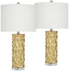 two gold lamps with white shades on each lamp and one is turned off to the side