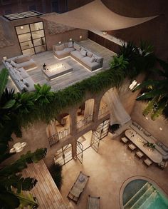 an aerial view of a house with a pool and patio area at night, surrounded by greenery