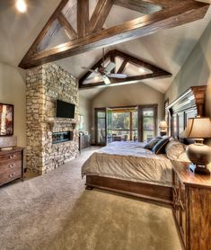 a large bedroom with a stone fireplace and vaulted ceiling