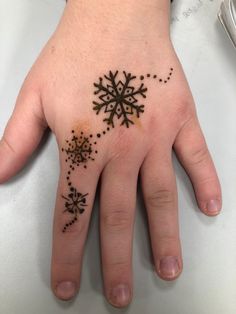 a person's hand with a black and brown snowflake tattoo on it