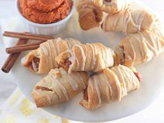 several pastries on a white plate with cinnamon sticks and dip in the bowl next to them