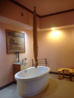 a bathroom with a large bathtub next to a sink and wooden bench in the corner