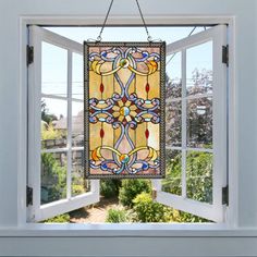 a stained glass window hanging from the side of a white frame with an ornate design on it