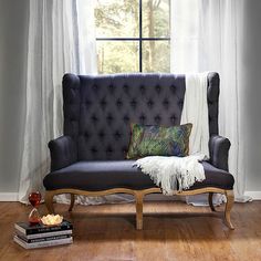 a couch sitting in front of a window next to a book shelf with books on it