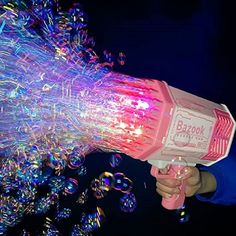 a person holding a pink and white blow dryer in their hand with bubbles coming out of it