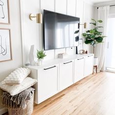 a flat screen tv mounted to the side of a white cabinet in a living room