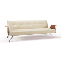 a white couch sitting on top of a metal frame sofa bed with wooden armrests