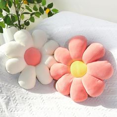 three flower shaped cushions sitting on top of a white table next to a potted plant