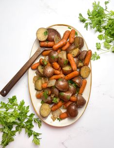 a plate with carrots, potatoes and parsley on it next to some parsley