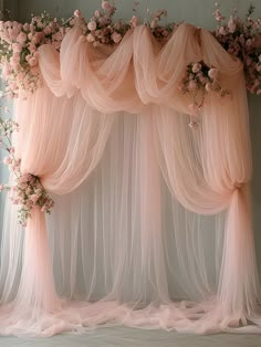 a pink wedding arch with sheer tulle and flowers