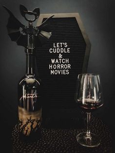 a bottle of wine next to a glass with the words let's cuddle and watch horror movies