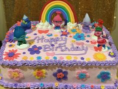 there is a birthday cake decorated with flowers and rainbows