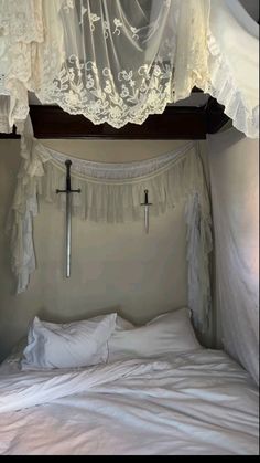 the bed is made up with white linens and crochet curtains over it