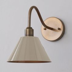 a wall light with a white shade hanging from it's side on the wall