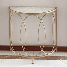 a white marble and gold metal table with two circles on the top, against a beige wall