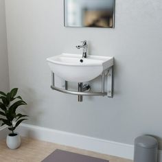 a white sink sitting under a mirror next to a potted plant