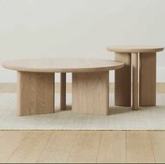 two wooden tables sitting on top of a white rug in front of a wall and floor