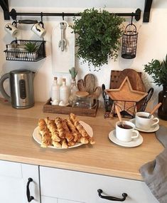 some food is sitting on a plate on the kitchen counter next to cups and saucers