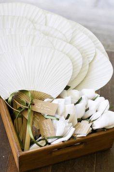 white plates and napkins in a wooden box on the floor with ribbons tied around them