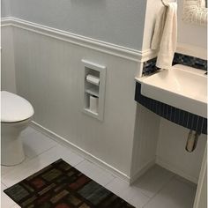 a white toilet sitting next to a bathroom sink under a faucet in a bathroom