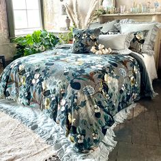 a bed covered in blue and white flowers next to a window with potted plants