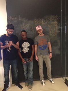 three men standing next to each other in front of a blackboard