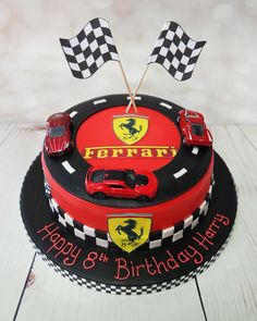 a birthday cake with cars on it and flags in the shape of a ferrari logo