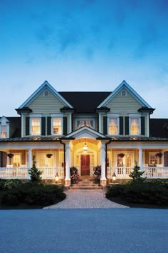 a large house lit up at night with lights on the front porch and side entrance